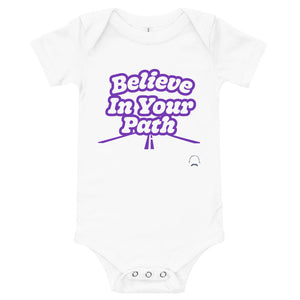 
                  
                    Load image into Gallery viewer, White baby onesie with Believe In Your Path text in white with purple outline and a road graphic at the bottom with Steve Harvey Head and Mustache outline in bottom corner
                  
                