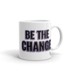 Image of white mug with "I Am The Change" font is black with purple outline and shadowing small Steve Harvey face in the lower right corner